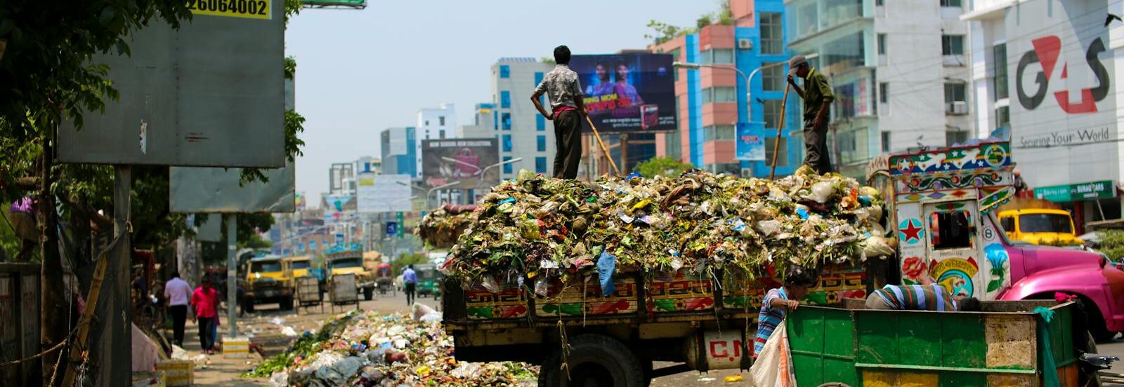 Photo by Kelly Trash-filled streets with vibrant urban buildings in Bangladesh.